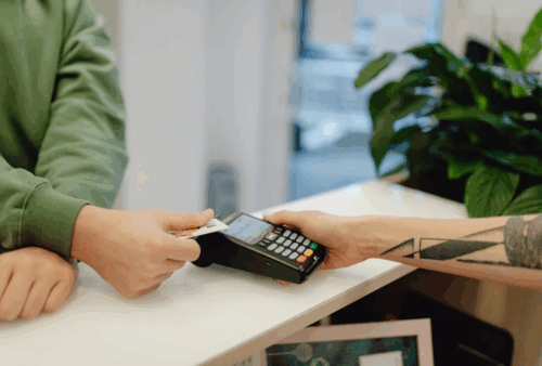 An image of a person paying with a card machine