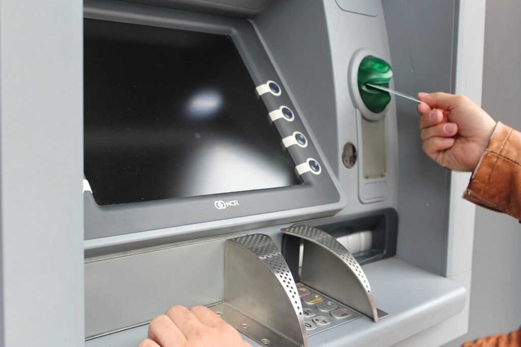 An image of a person entering their debit card into an ATM