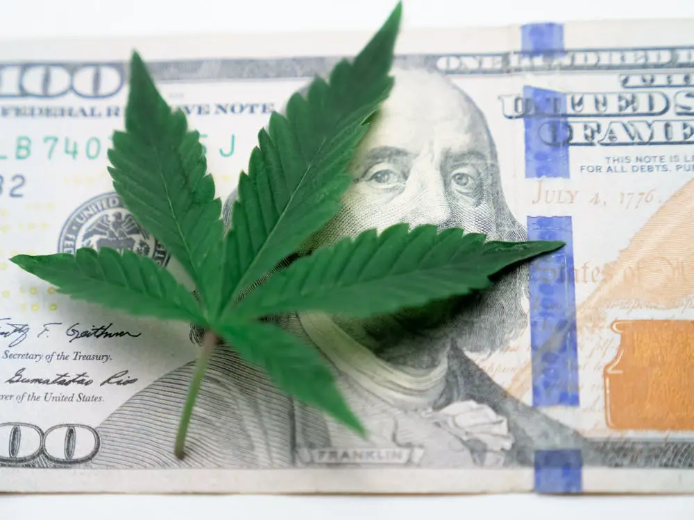 cannabis leaf placed on US currency symbolizing improved cash flow and financial flexibility through ATM leasing for dispensaries